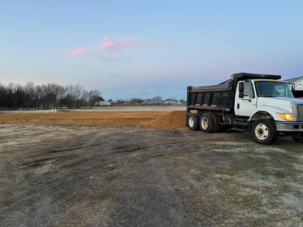 Dump truck spreading fill material for a new house pad